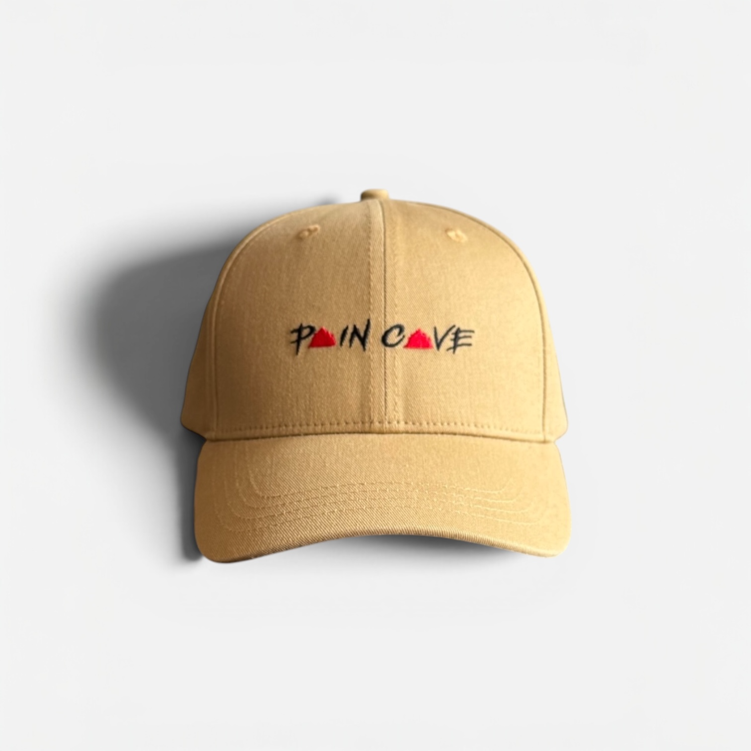 Pain Cave desert sand snapback cap with embroidered logo on light grey background